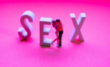 coppia abbracciata in miniatura con scritta SEX su sfondo fucsia