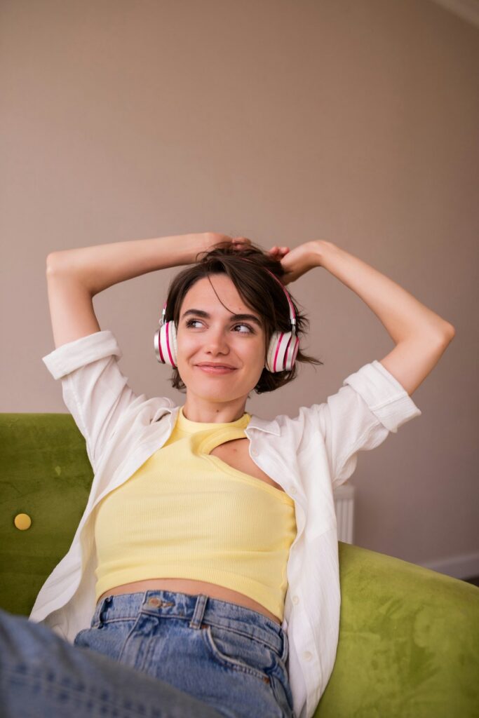 Donna seduta su un divano con le cuffie, immersa in un momento di ascolto intimo