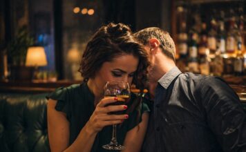 Coppia adulta seduta vicina in un ambiente intimo mentre condivide un momento di complicità e attrazione