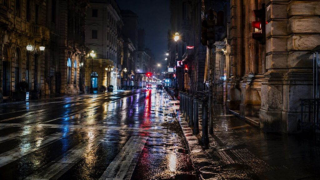 Strada urbana notturna con luci sfocate e atmosfera malinconica