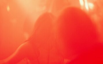 Immagine sfocata di due persone in atmosfera rossa simbolo di desiderio e fantasie sessuali