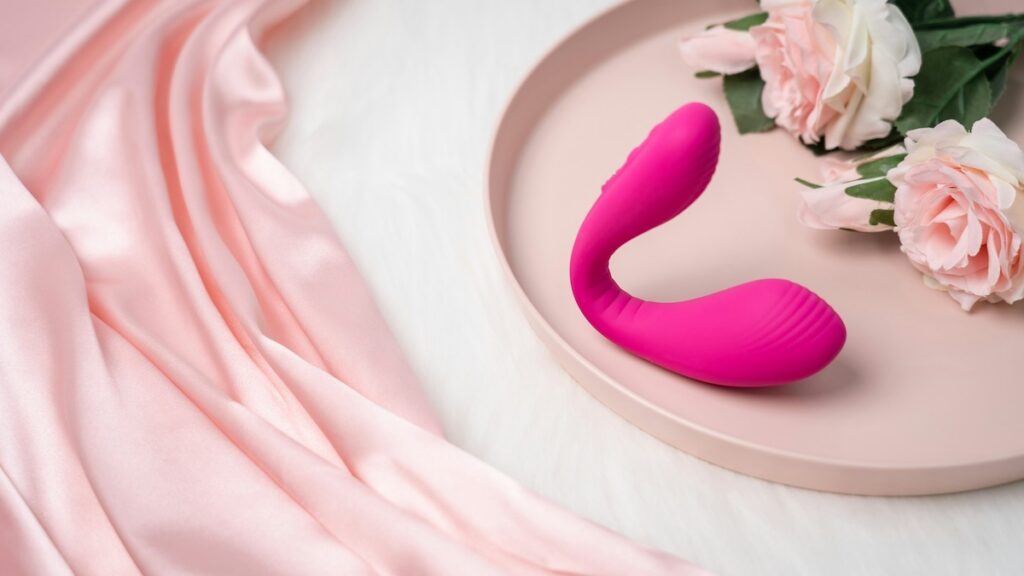Vibratore rosa appoggiato su un piatto rosa, immagine minimal dedicata alla scelta di un sex toy discreto