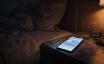 Smartphone con chat generica su comodino in un contesto di intimità digitale