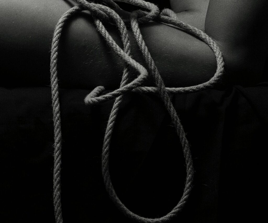 Foto in bianco e nero di una persona che tiene una corda, immagine sul tema del sesso, del bdsm consapevole e del consenso
