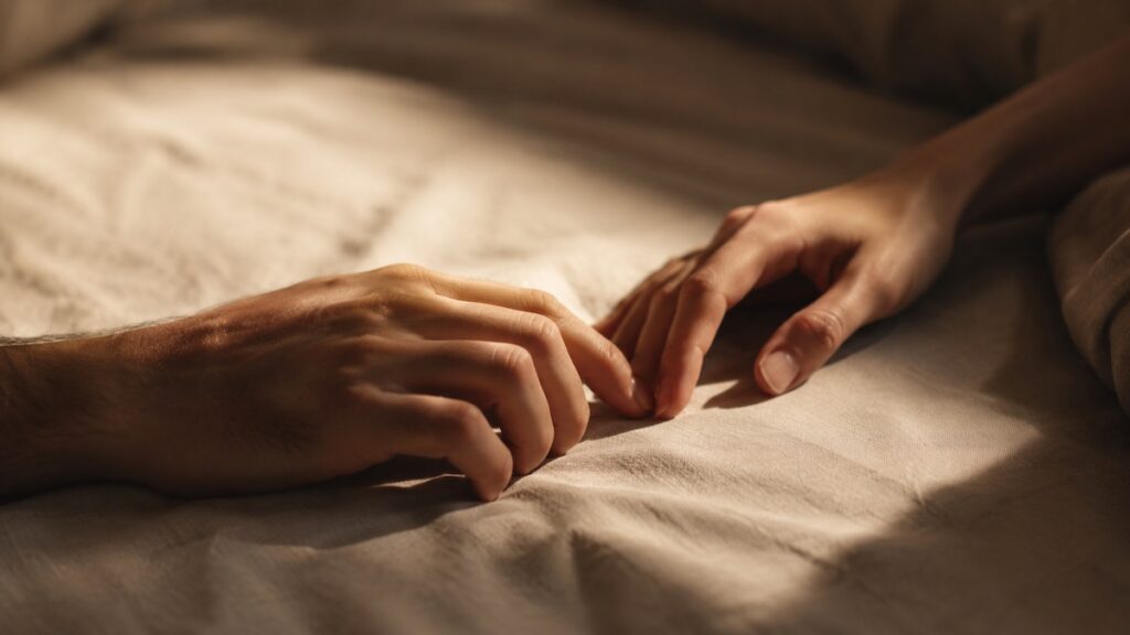 Due mani adulte che si sfiorano delicatamente in una luce calda
