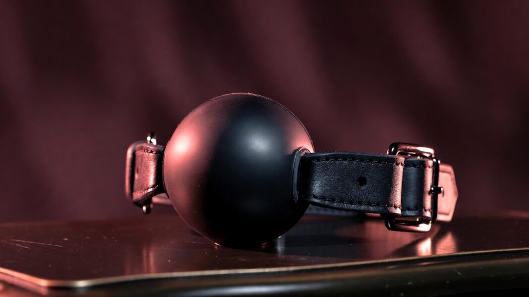 Ballgag nera con cinturino in pelle, accessorio utilizzato nei giochi BDSM.