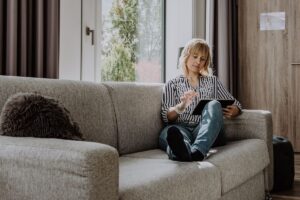 Donna matura seduta comodamente sul divano con un tablet