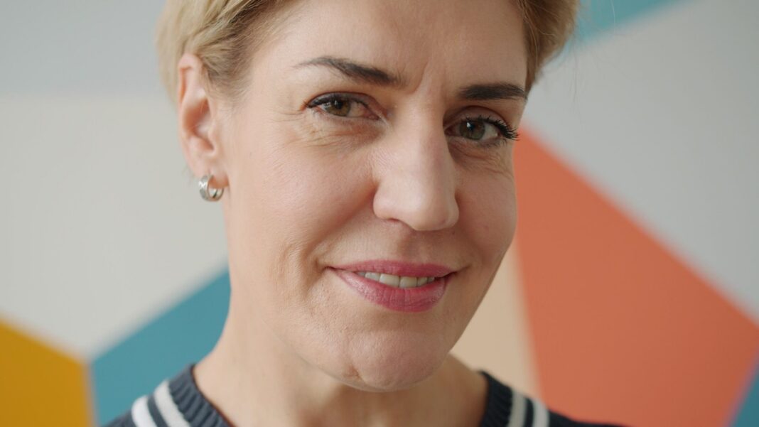 Donna adulta sorridente in un ambiente contemporaneo, immagine dedicata al coaching femminile