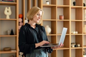 Donna di circa 45-50 anni lavora al computer da casa durante una sessione di coaching online.