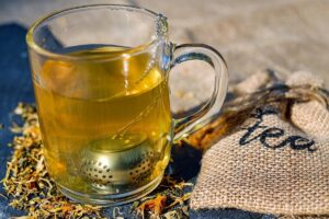 Tisana alle erbe accompagnata da foglie verdi