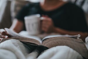Donna di mezza età che legge un libro seduta a letto